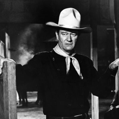 Actor John Wayne wears a Western outfit in a doorway in a still from 'The Man Who Shot Liberty Valance.'