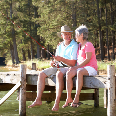 Senior couple sitting on a lakeside dock and fishing