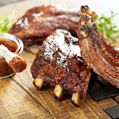 Grilled and smoked ribs with barbeque sauce on a carving board