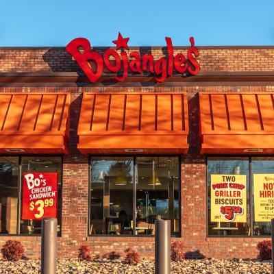 Exterior view of a Bojangles’ Famous Chicken ’n Biscuits restaurant at sunset, with brand signage against a clear blue sky.