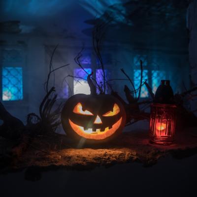 Scary Halloween pumpkin with a spooky house in the distance.