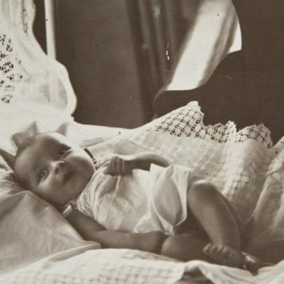 Baby girl laying in bed, circa 1920s.