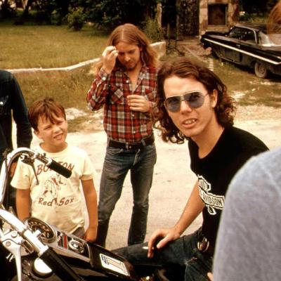 Friends standing around a guy on a motorcycle