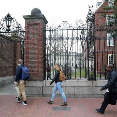 People walk through Harvard University's campus with a box in Cambridge, MA