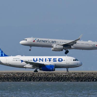A United Airlines plane is taxiing to takeoff as an American Airlines plane lands at San Francisco International Airport
