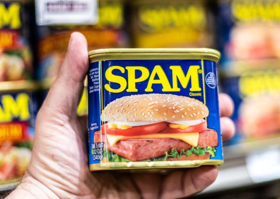 Hand holding Spam can in supermarket.