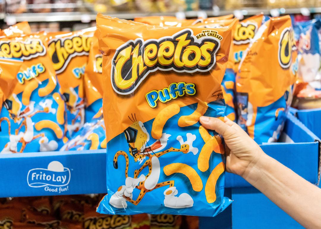 Hand holding a bag of Cheetos in supermarket.