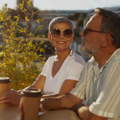 An older couple sitting outdoors at the table in warm sunlight.