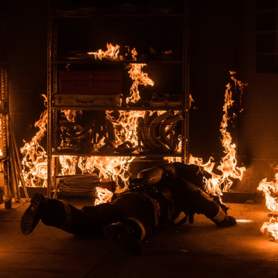 A fireman on the floor in a burning room.