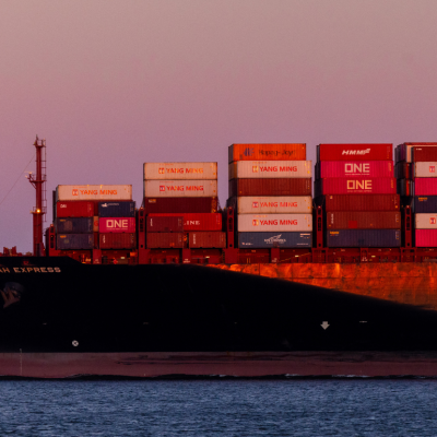 A container ship next to a full moon.