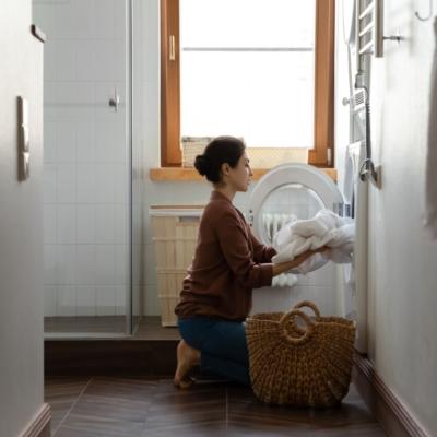 A woman putting laundry into a washing machine.