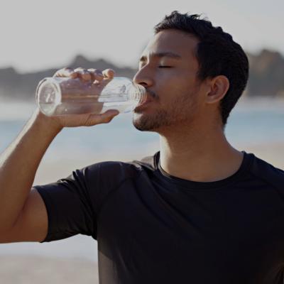 A young man tilting a water bottle to his mounth. 