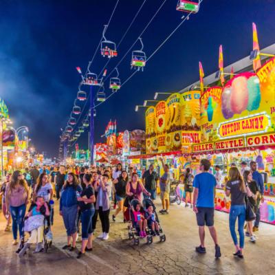 Crowds of families at the Arizona State Fair surrounded by colorful lights, games and concession stands.