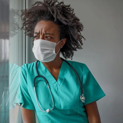 A masked female nurse looking distressed. 