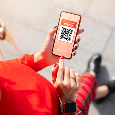 A woman looking at a QR code coupon on her smartphone.