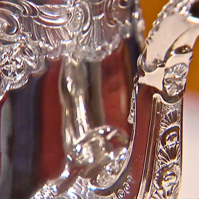 Closeup of an ornate silver teapot.