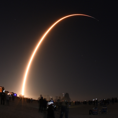 A long exposure of a light going across the sky at night showing a SpaceX rocket launching a Starlink mission.