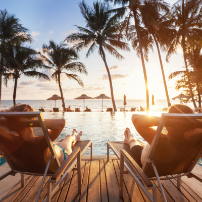 Two people sitting in chairs by a pool overlooking the ocean.