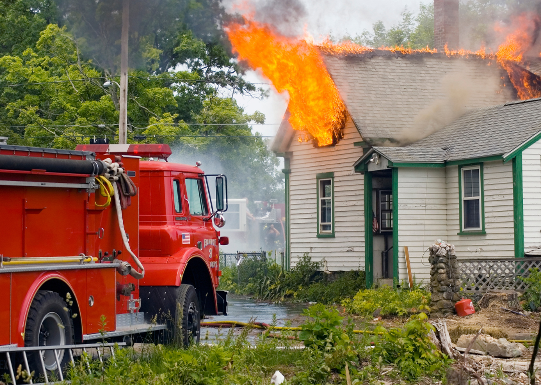 A house on fire with a fire truck outside.