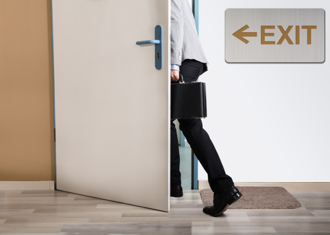 A businessperson leaving the office through a door marked with an exit sign.