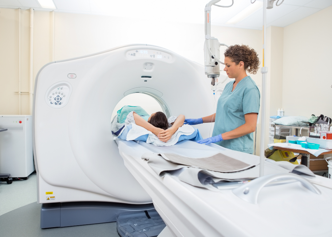 A nurse preparing a patient for a CT scan in a hospital room