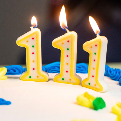 A 111-year-old's birthday cake with three lit number one candles.