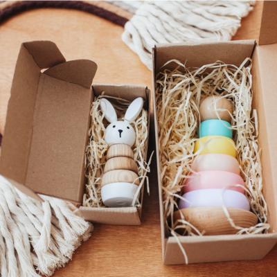 Wooden baby toys in boxes in front of a rainbow toy made of rope.