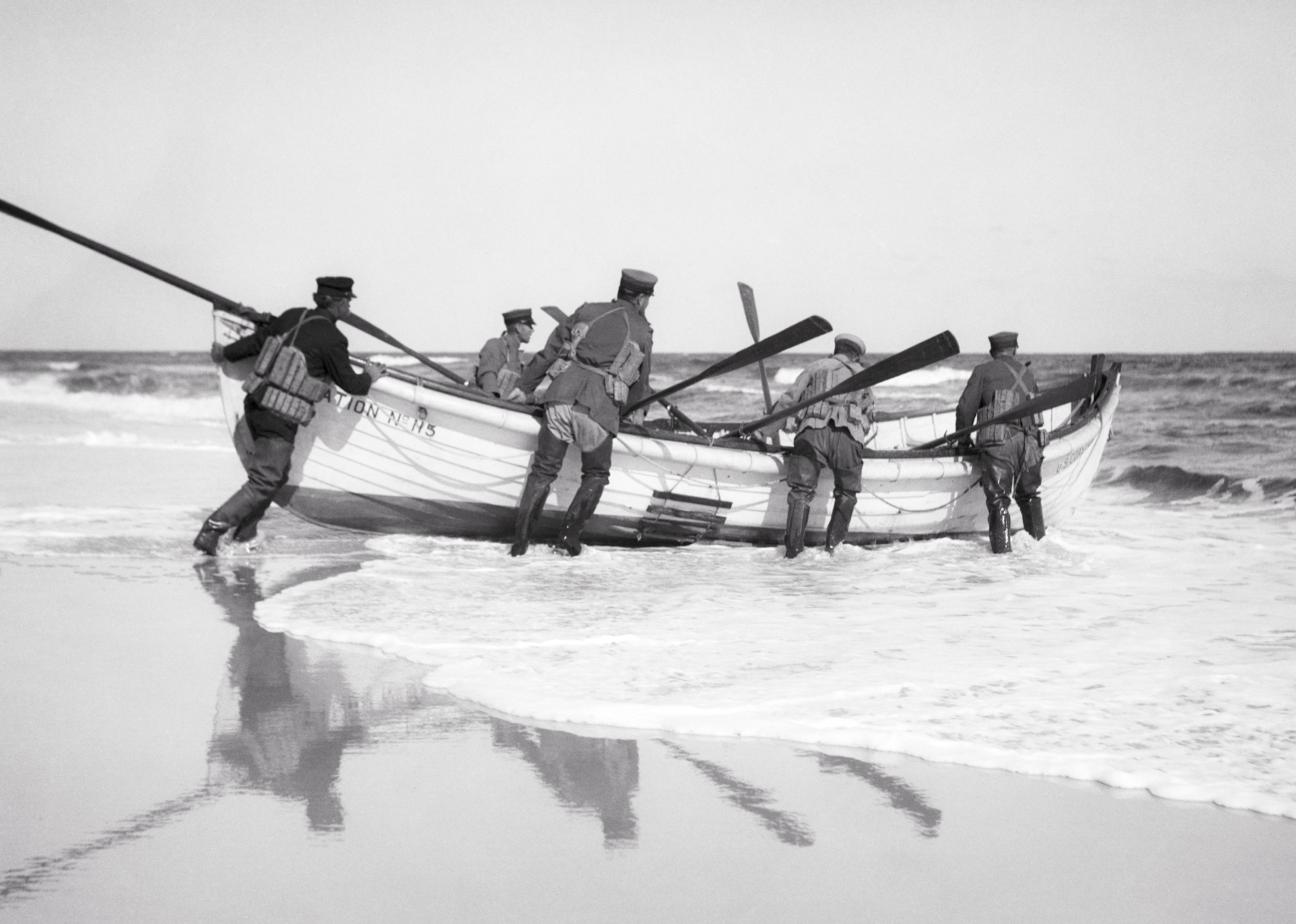 U.S. Coast Guard launching a wooden rescue boat on the beach.
