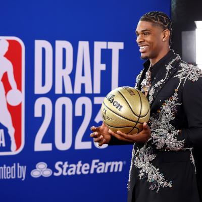 Scoot Henderson holding a golden basketball standing in front of a backdrop for the 2023 NBA Draft.