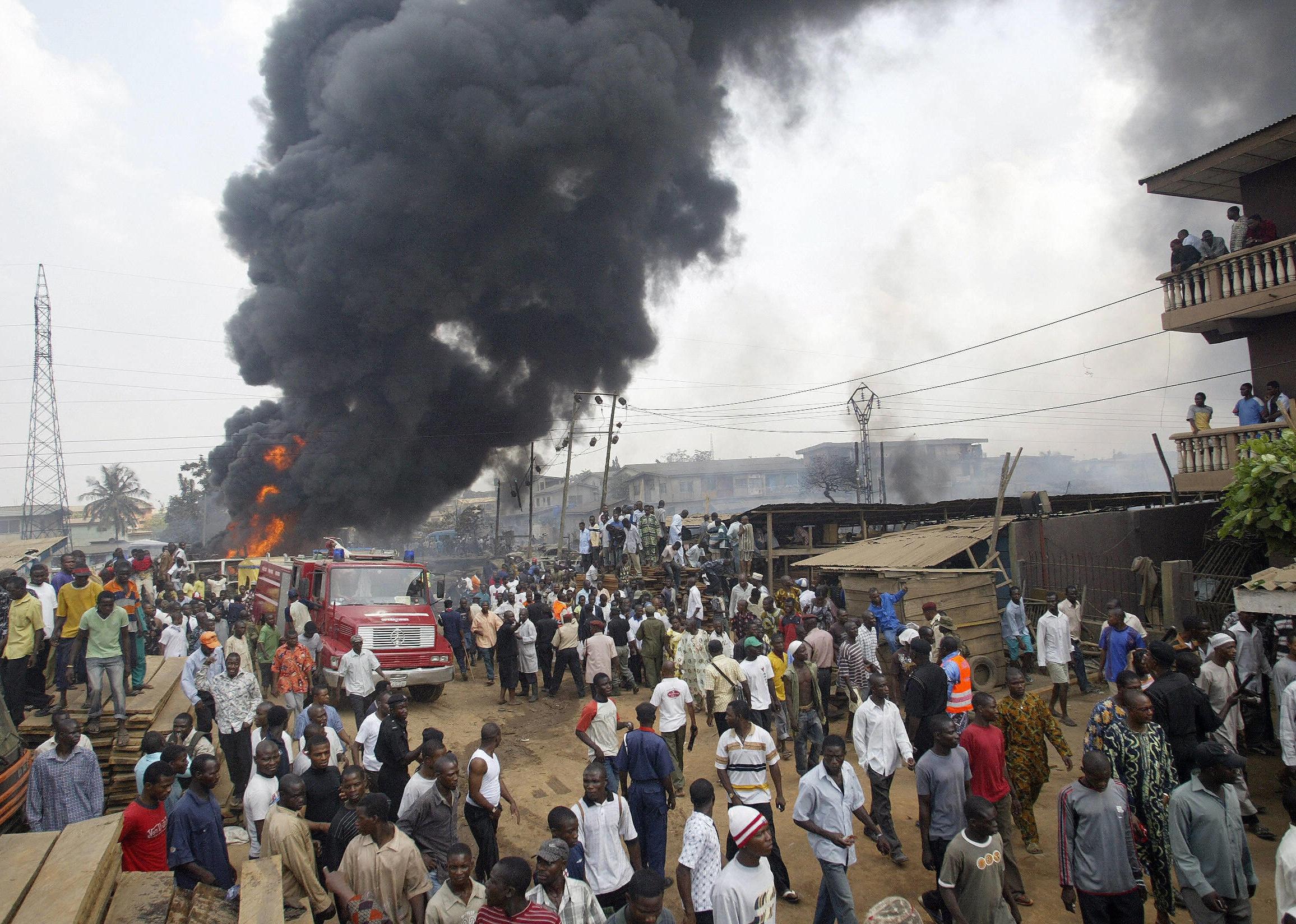Bystanders watch fire fighters trying to put out a fire after the explosion of a pipeline.