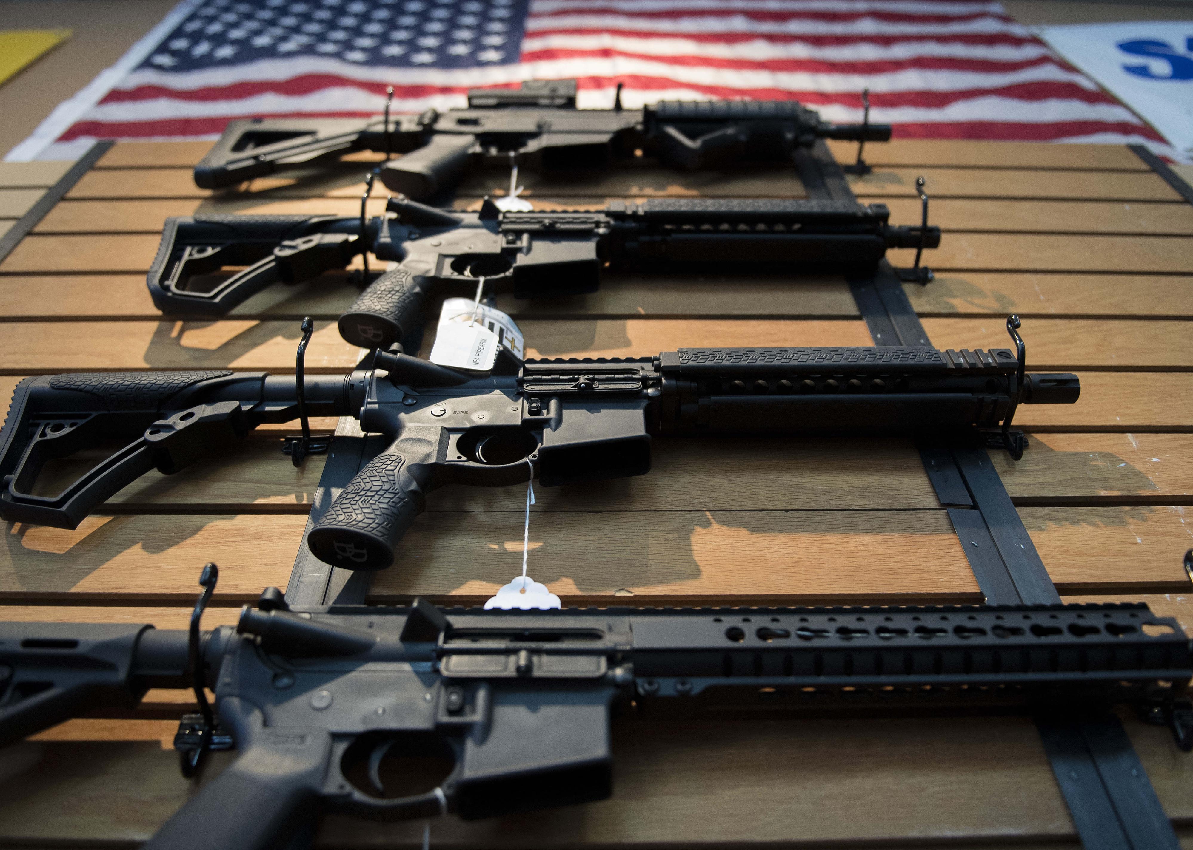 Large guns hanging in a gun shop with an American flag on top.