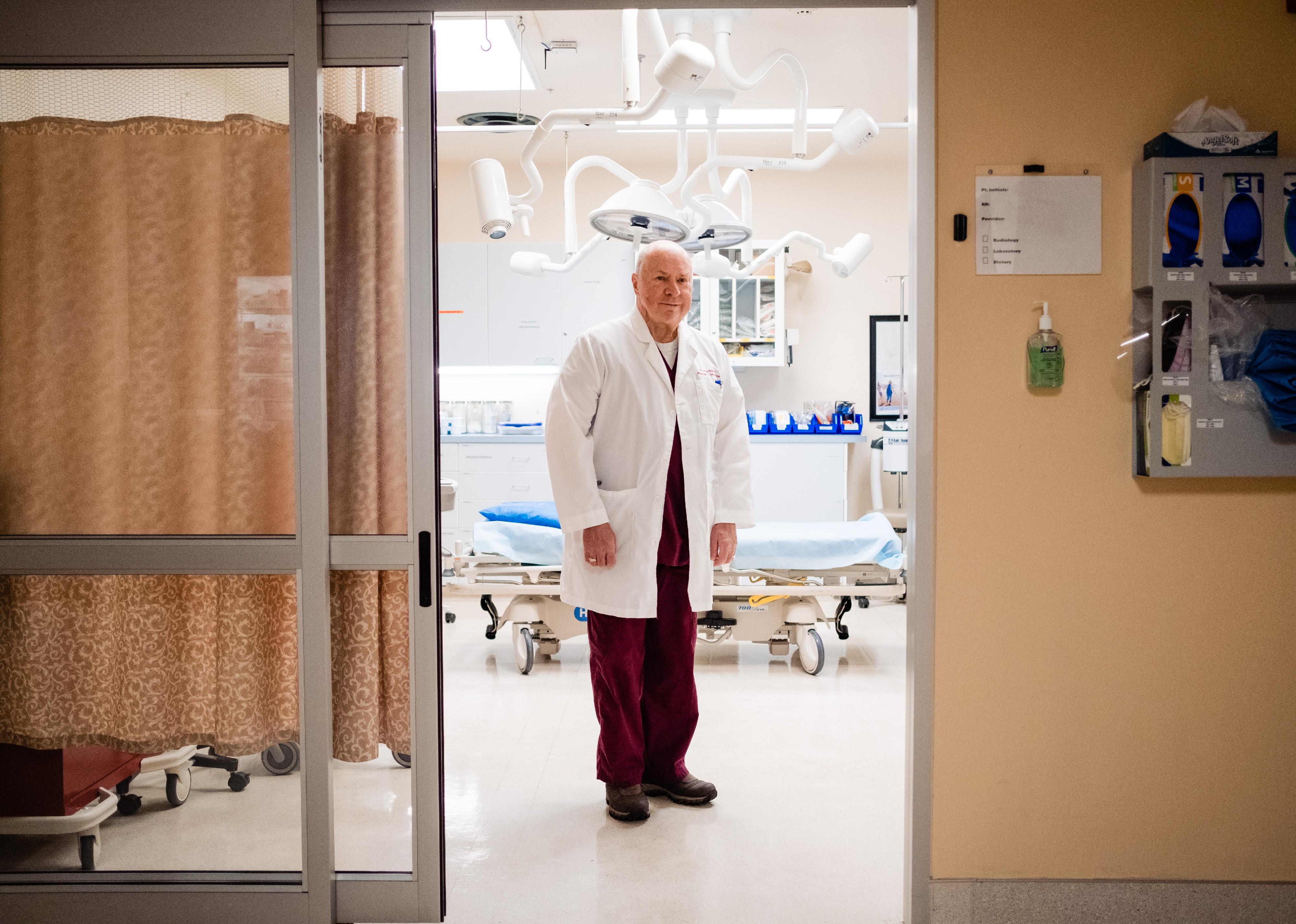 A doctor standing in the doorway of a hospital room.