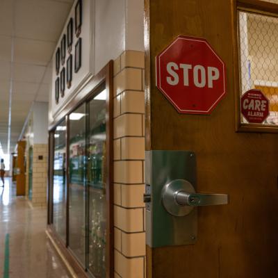 Almost empty hallway of a school with a stop sign on a door.
