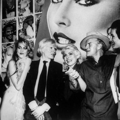 Bob Colacello, Jerry Hall, Andy Warhol, Debbie Harry, Truman Capote and Paloma Picasso at a party.