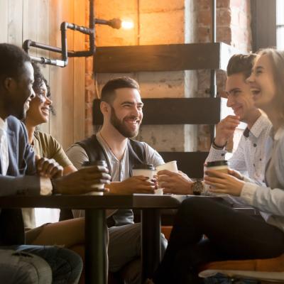 Group of friends having fun and laughing drinking coffee in coffeehouse.