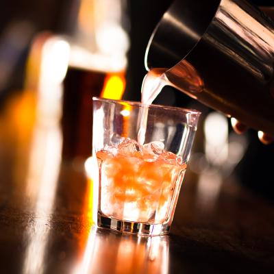 Barman pouring a cocktail into a glass.