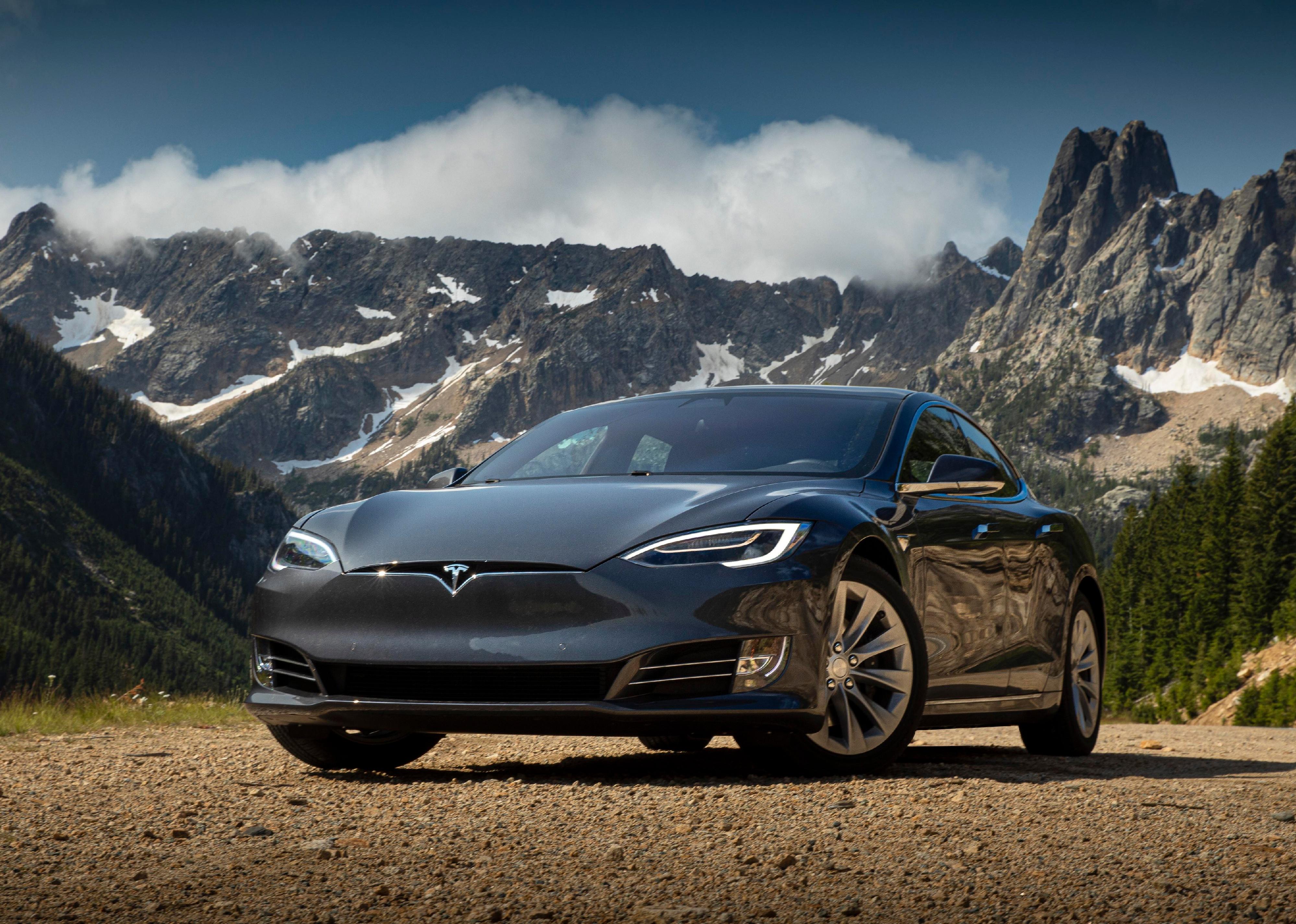 Tesla model 3 in front of a mountain.