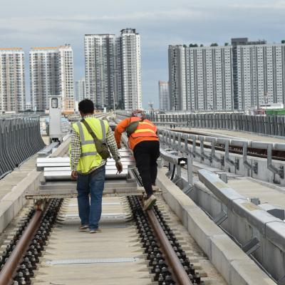 Workers moving equipment on a railway.