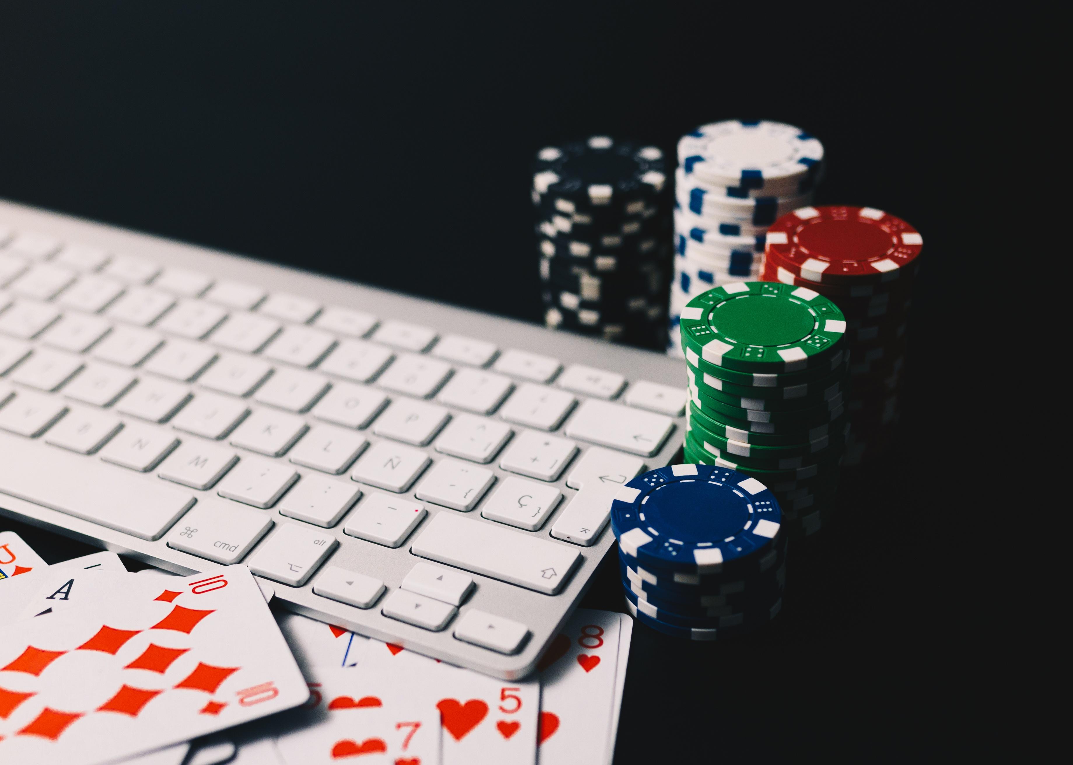 Poker chips and cards surrounding a computer keyboard.