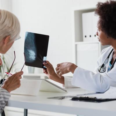 Female doctor talks to a female patient while looking at mammogram