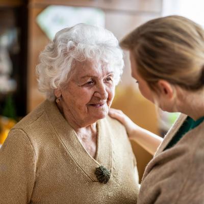 Health care worker talking to an older woman during a home visit.