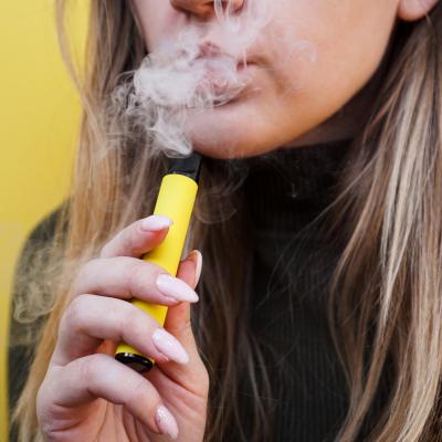 A young woman uses a disposable electronic cigarette.
