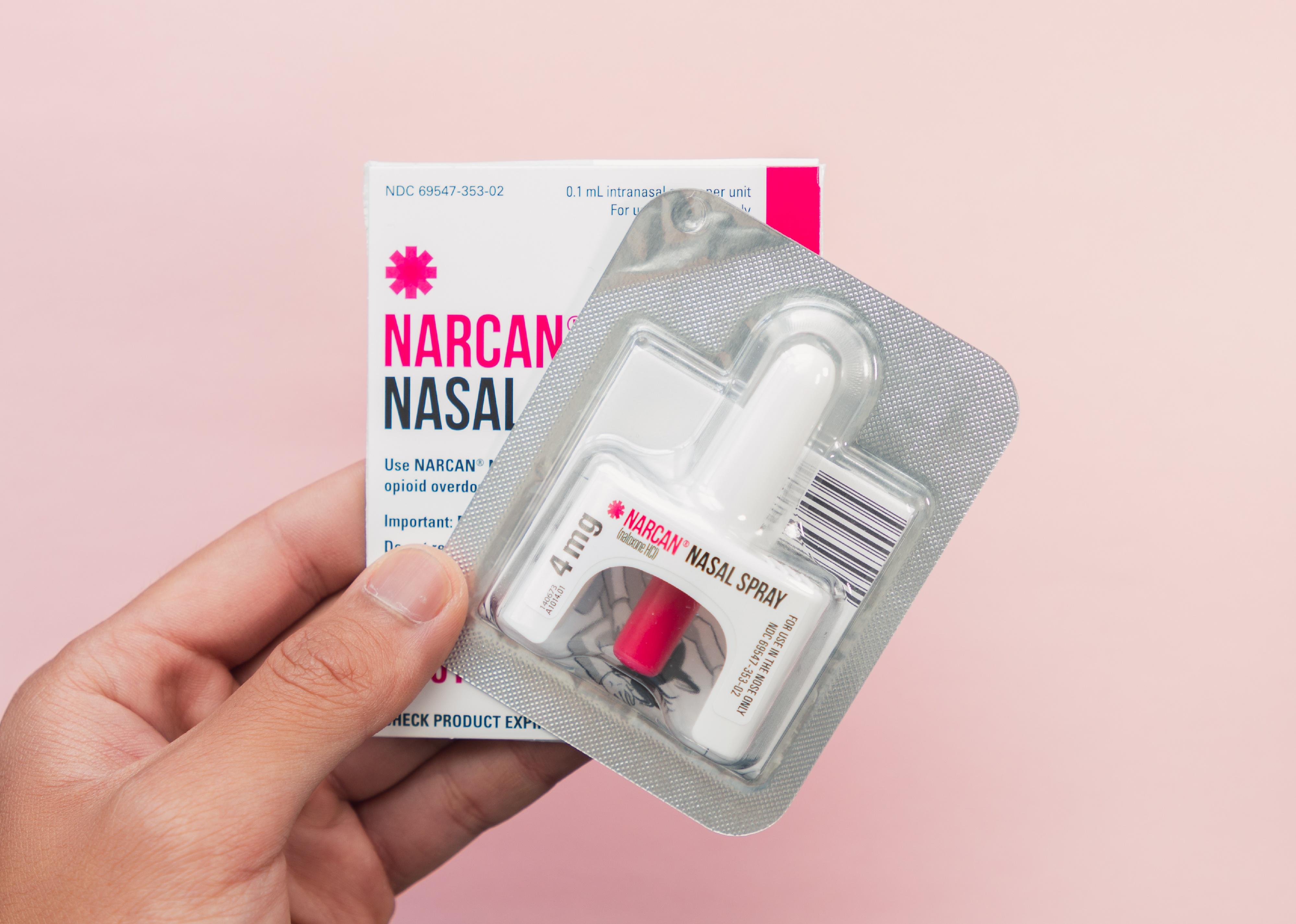 Hand holding a Narcan Evzio Naloxone nasal spray.