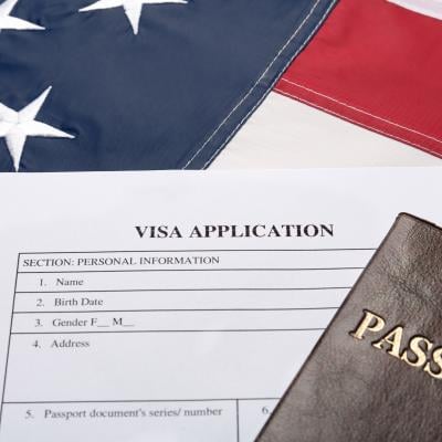 Visa application form and passport on American flag.