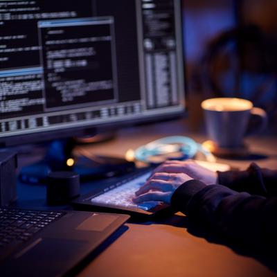 Close up of hacker in dark room writing code.