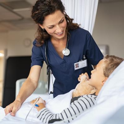 A nurse taking care of little boy hospitalized in a bed.