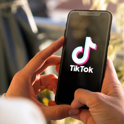 Person holding a smartphone with the TikTok app open.