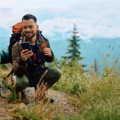 Young man on a smartphone while hiking in the mountains.