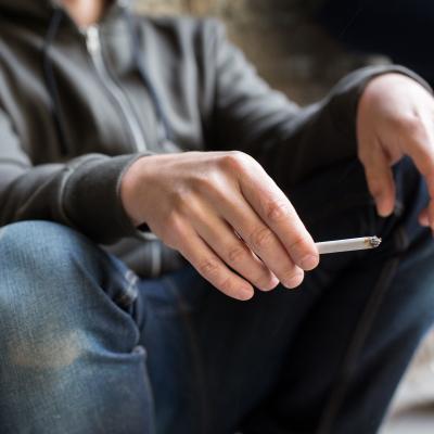 Closeup of young man smoking cigarette outdoors.