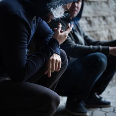 Close up of two young men smoking cigarettes outdoors.